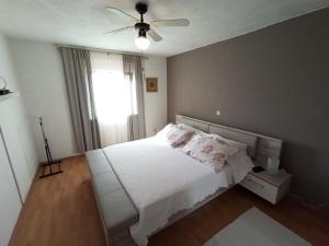 1 dormitorio con cama blanca y ventilador de techo en Sonja Apartment en Premantura