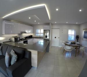 a kitchen and living room with a couch and a table at Stylish Sea View Apartment in Santorini Estate. in Ballito