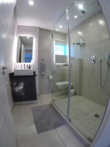 a bathroom with a shower and a toilet and a sink at Stylish Sea View Apartment in Santorini Estate. in Ballito