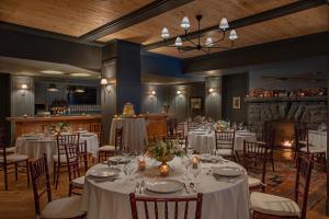 uma sala de jantar com mesas e cadeiras com lençóis brancos em Grand Adirondack Hotel, Lake Placid, a Tribute Portfolio Hotel em Lake Placid