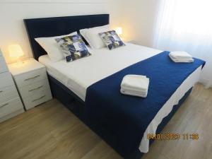 een slaapkamer met een bed met blauwe en witte lakens en kussens bij Peacock Apartment in Split