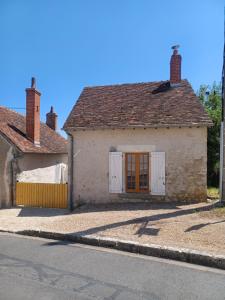 a white house with a brown door and a street at La P'tite Maison in Coulanges