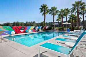 a swimming pool with lounge chairs and palm trees at Aloft Jacksonville Airport in Jacksonville