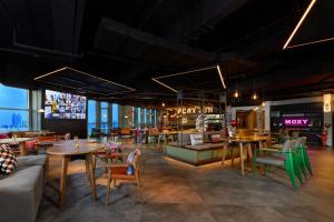 a restaurant with tables and chairs and a tv at Moxy Shanghai Xuhui in Shanghai