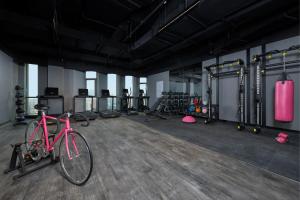 een roze fiets geparkeerd in een sportschool met gewichten bij Moxy Shanghai Xuhui in Shanghai