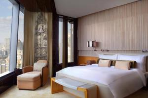 a bedroom with a large white bed and a chair at The Ritz-Carlton Shanghai, Pudong in Shanghai