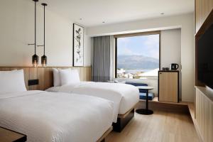 two beds in a hotel room with a large window at Fairfield by Marriott Kyoto Amanohashidate in Miyazu
