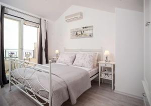 a white bedroom with a bed and a window at Charming stone villa Silva in Tučepi