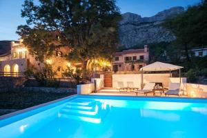 a swimming pool in front of a house at Charming stone villa Silva in Tučepi