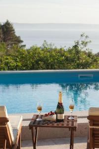Charming stone villa Silva في توسيبي: طاولة مع زجاجة من النبيذ وكأسين