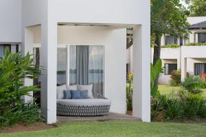 Cette maison blanche dispose d'une terrasse avec un canapé. dans l'établissement Sheraton Fiji Golf & Beach Resort, à Denarau