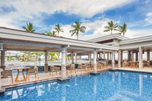 een zwembad met tafels en stoelen naast een gebouw bij Sheraton Fiji Golf & Beach Resort in Denarau