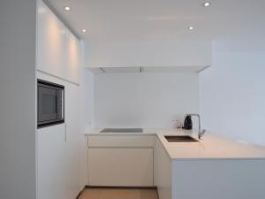 uma cozinha branca com um lavatório e um balcão em Aaron 0201 apartment with 2 sunny terraces em De Haan