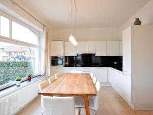eine Küche mit einem Holztisch und weißen Schränken in der Unterkunft Hofstad Verde 0001apartment on the ground floor in De Haan