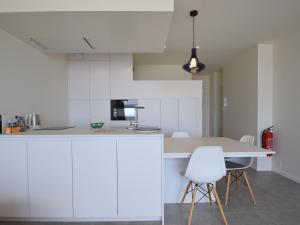 een keuken met witte kasten en een tafel en stoelen bij Mayfair 0205 exclusive residence with sea view in De Haan