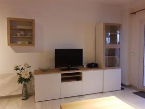 a living room with a television on a white cabinet at Komfortable Ferienwohnung erste Strandreihe Playa Burriana in Nerja
