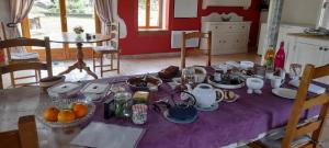 una mesa con un mantel púrpura con fruta. en Chambres et table d'hôtes : LES SENTIERS DE LA BREME 