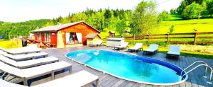 een zwembad op een terras met stoelen en een cabine bij Ośrodek Wczasowy Na Borach in Korbielów