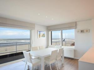 een witte eetkamer met een witte tafel en stoelen bij Golf 0301 apartment with modern kitchen by the sea in De Haan