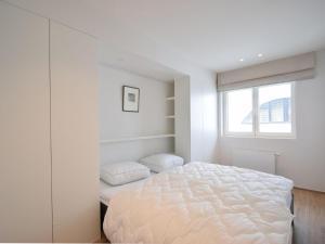 een witte slaapkamer met een bed en een raam bij Golf 0301 apartment with modern kitchen by the sea in De Haan