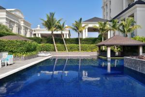 a swimming pool in front of a building with palm trees at Sheraton Grand Palace Indore in Indore