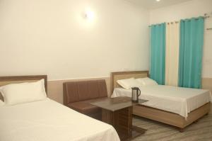 Cette chambre comprend deux lits et une table avec un canapé. dans l'établissement Panwar Palace, à Uttarkāshi