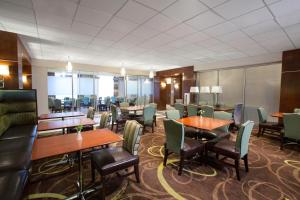 Sheraton Pittsburgh Airport Hotel في كوراوبوليس: غرفة طعام مع طاولات وكراسي ونوافذ