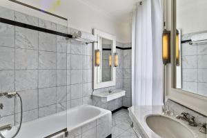 a white bathroom with a tub and a sink at Le Dokhan's Paris Arc de Triomphe, a Tribute Portfolio Hotel in Paris