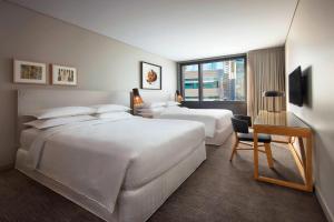 a hotel room with three beds and a desk at Four Points by Sheraton Sydney, Central Park in Sydney