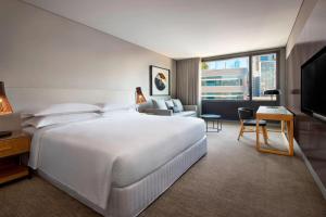 a hotel room with a large white bed and a television at Four Points by Sheraton Sydney, Central Park in Sydney