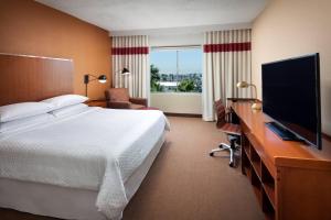 a hotel room with a bed and a desk with a television at Four Points by Sheraton Los Angeles International Airport in Los Angeles