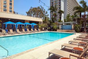 a large swimming pool with chairs and blue umbrellas at Four Points by Sheraton Los Angeles International Airport in Los Angeles