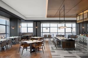 een restaurant met tafels en stoelen en grote ramen bij Shenyang Marriott Hotel in Shenyang