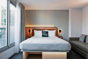 1 dormitorio con cama y ventana grande en Moxy Paris Bastille en París
