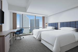 a hotel room with two beds and a desk at Four Points by Sheraton Surabaya, Pakuwon Indah in Surabaya