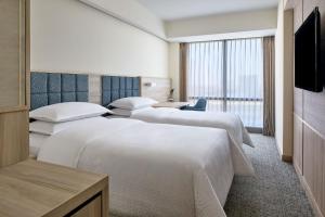 a hotel room with three beds and a flat screen tv at Four Points by Sheraton Surabaya, Pakuwon Indah in Surabaya