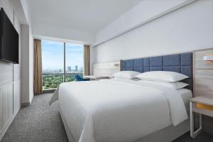 a hotel room with a large bed and a television at Four Points by Sheraton Surabaya, Pakuwon Indah in Surabaya