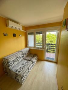 uma sala de estar com um sofá e uma janela em Viktória Apartman em Balatonalmádi