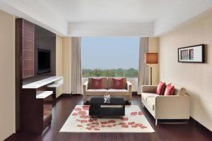 a living room with two couches and a tv at Jaipur Marriott Hotel in Jaipur