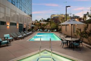 a pool with tables and chairs next to a building at Sheraton Cerritos in Buena Park