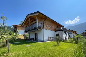 a house with a wooden roof and a green yard at Chalet Charivari Inzell mit Whirlpool, Sauna & Garten in Inzell
