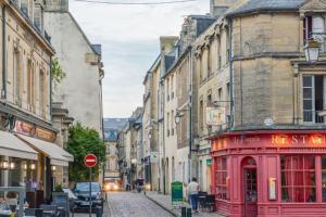 バイユーにあるLe petit Bayeusainの街路に赤い電話ボックスがある通り