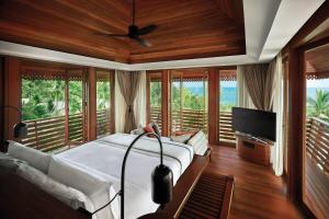 a bedroom with a bed and a tv and windows at The Ritz-Carlton, Koh Samui in Choeng Mon Beach