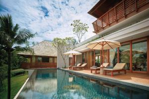 a house with a swimming pool with chairs and an umbrella at The Ritz-Carlton, Koh Samui in Choeng Mon Beach