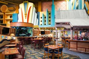 un restaurant avec des tables, des chaises et des planches de surf sur le mur dans l'établissement Four Points by Sheraton Cocoa Beach, à Cocoa Beach