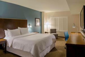 a hotel room with a large bed and a chair at Four Points by Sheraton Cocoa Beach in Cocoa Beach