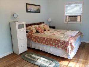 a bedroom with a bed and a dresser and a window at Saybrook Manor Beach House in Old Saybrook