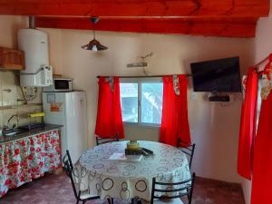 - une cuisine avec une table et des rideaux rouges dans l'établissement Apart Los Ciruelos, à Huerta Grande