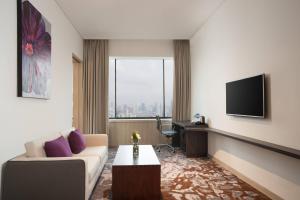 ein Wohnzimmer mit einem Sofa und einem TV in der Unterkunft Four Points by Sheraton Jakarta Thamrin in Jakarta