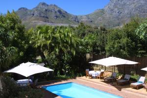 a swimming pool with umbrellas and a table and chairs at Floreal House in Cape Town